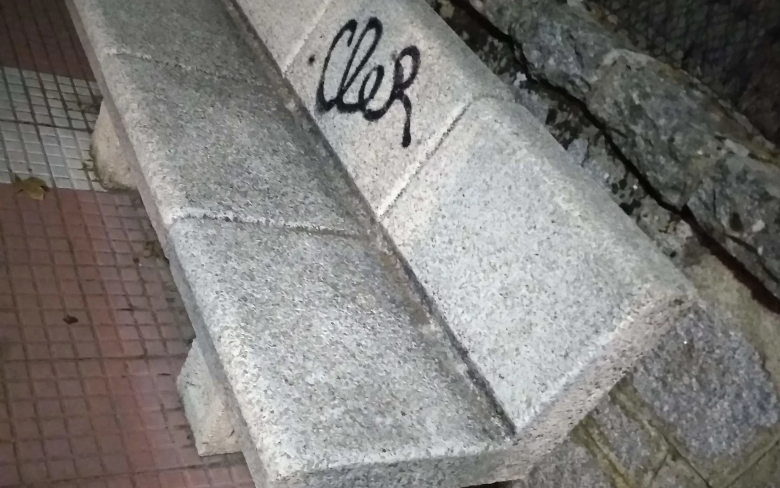 Imagen de un banco de piedra en una calle, de noche.